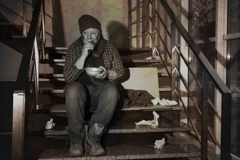 alter Mann sitzt auf einer Wohnungstreppe, und isst.
